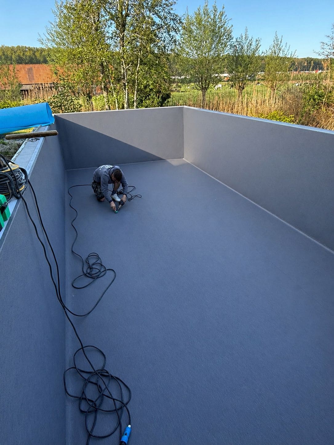 Vakman last een zwembadliner op maat tijdens professionele plaatsing door Liner Plaatsen